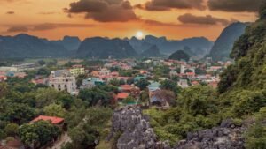 Beautiful landscape of Ninh Bình with mountains and colorful town at sunset.