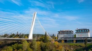 a large white bridge over a river next to a tall building
