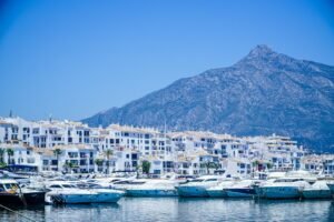 white and blue boats on sea near mountain under blue sky during daytime