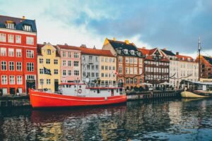 A bright red boat moored in Nyhavn canal before colorful historic buildings in Copenhagen