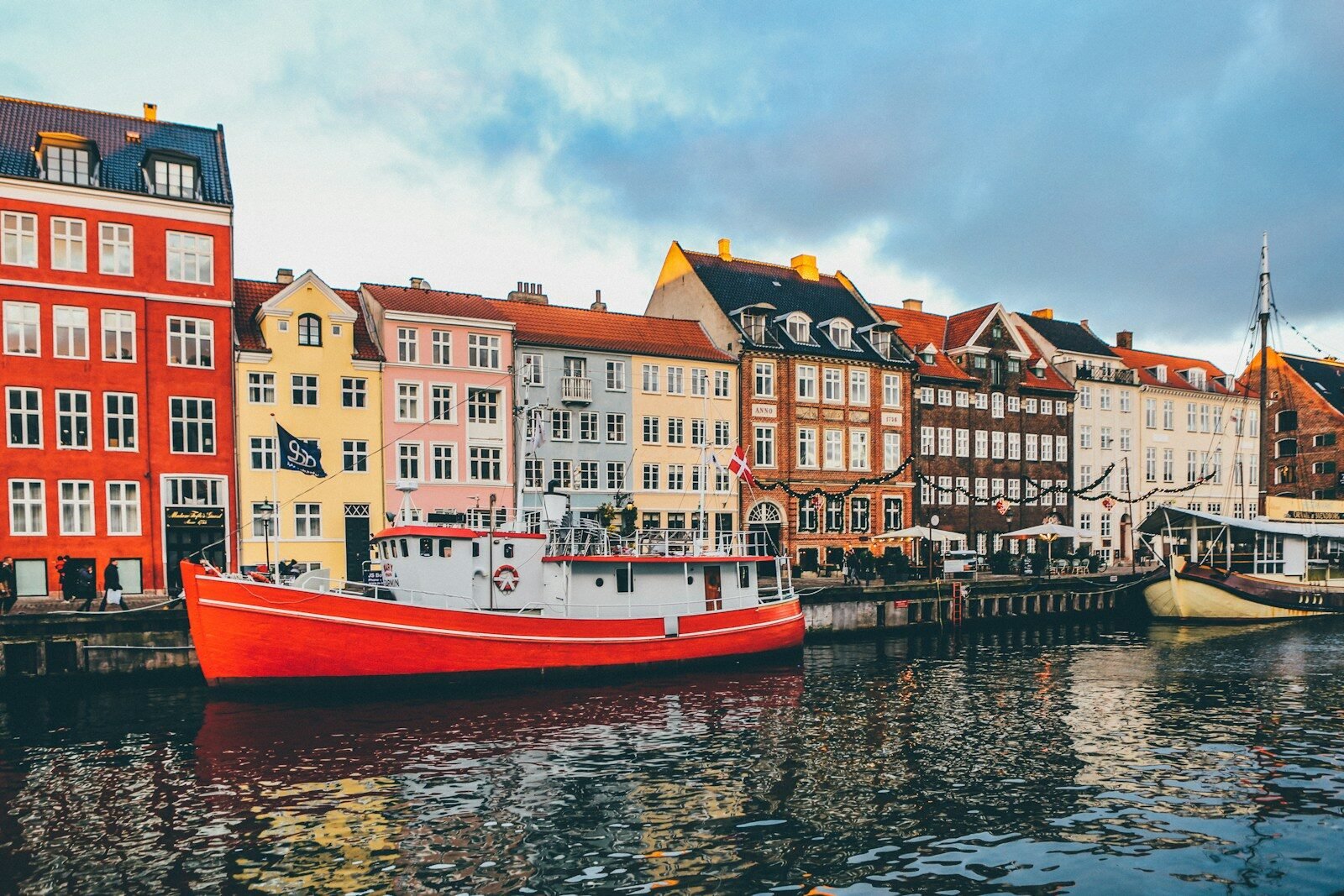 A bright red boat moored in Nyhavn canal before colorful historic buildings in Copenhagen