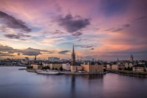 The Riddarholmen Church spire rising above the Stockholm waterfront under a purple sky