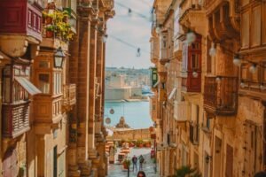 A narrow street in Valletta with traditional wooden balconies overlooking the Grand Harbour